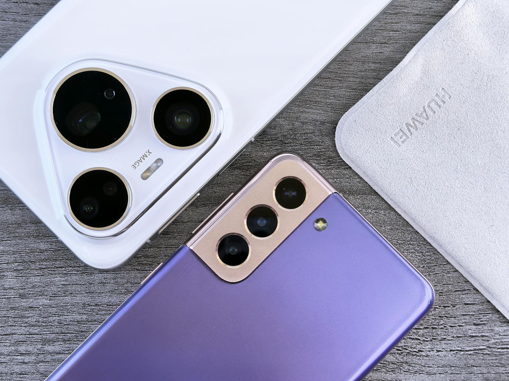 Close-up of two smartphones with camera focus on a textured wooden surface.