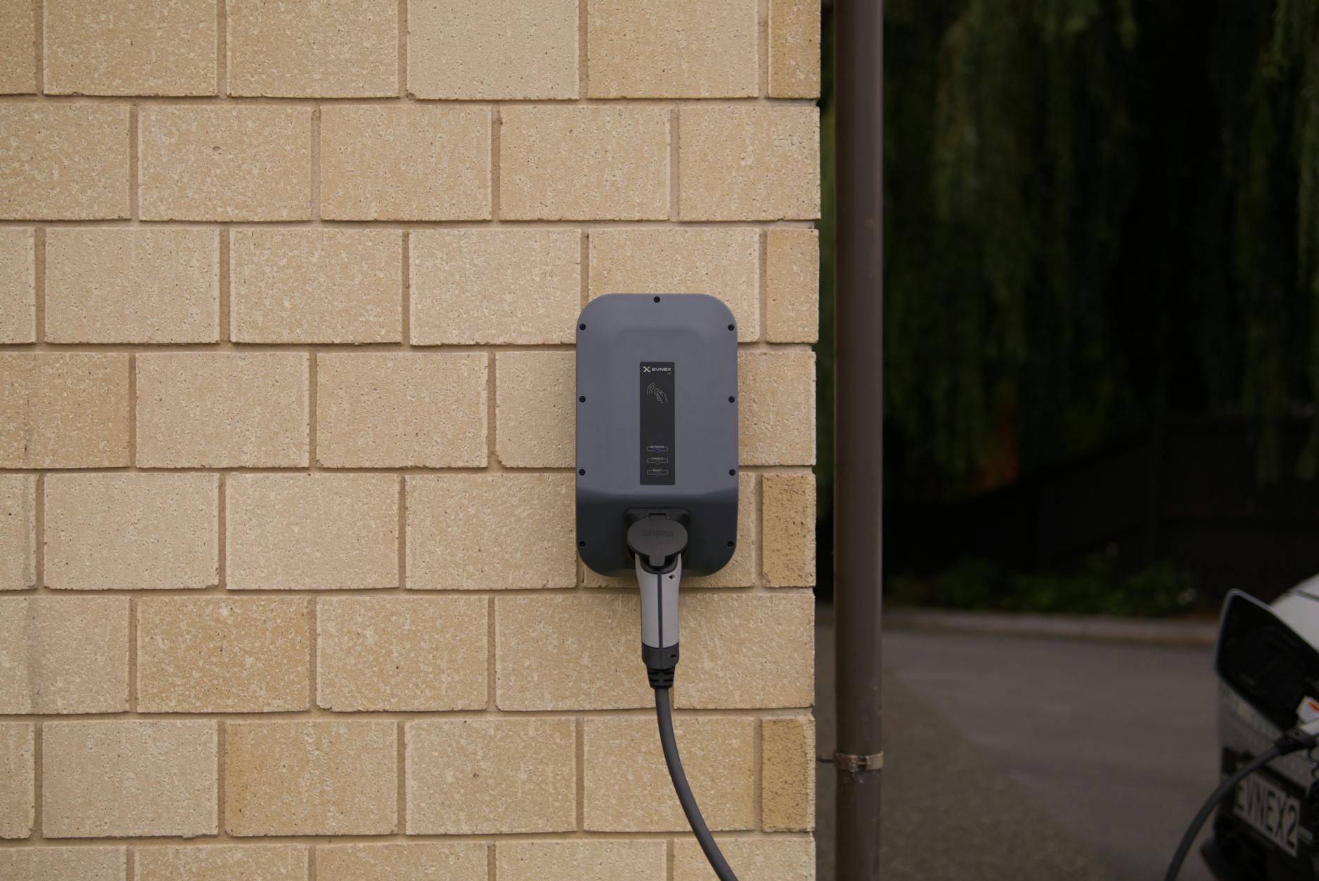 A wall-mounted electric vehicle charging station installed on a brick wall in Christchurch, New Zealand.